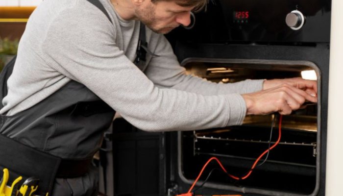 Appliance repair technician repairing an oven in a New Jersey kitchen